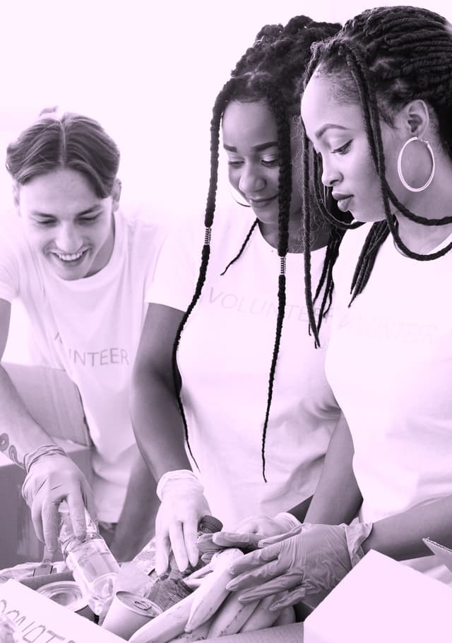 Image of a group of high school volunteers smiling and organizing brown bags of food items